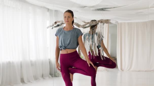 Fiatal nő csinál jóga fa pózol stúdióban — Stock videók