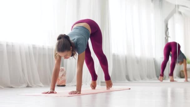 Vrouw doet neerwaarts gerichte hond pose in yoga studio — Stockvideo