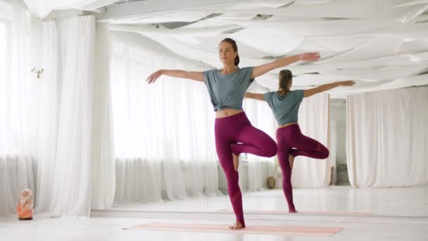 Junge Frau posiert mit Yoga-Baum im Studio — Stockvideo