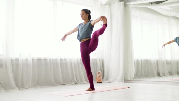 Mujer haciendo yoga de la mano a los pies grandes pose en el estudio — Vídeo de stock