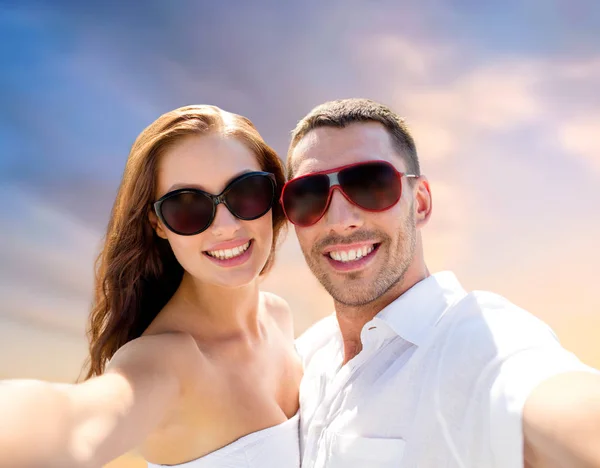 Улыбающаяся пара в солнечных очках делает селфи — стоковое фото