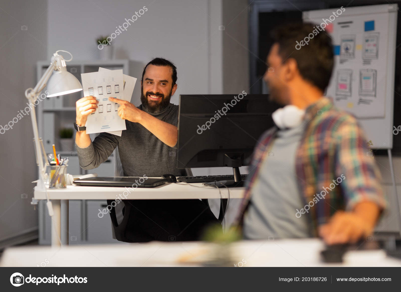 Creative Man Showing Papers To Colleague At Office Stock Photo