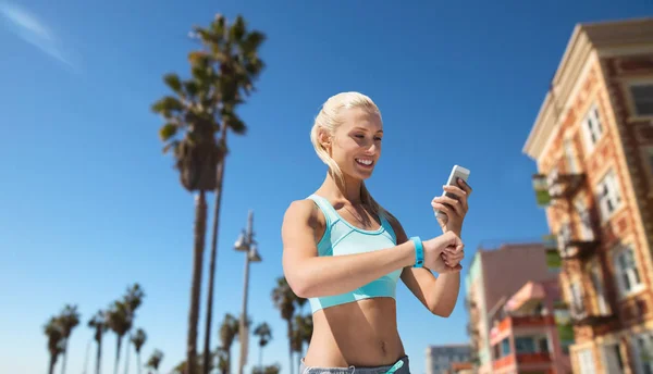 Femme heureuse avec tracker de fitness et smartphone — Photo