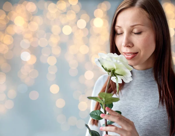 Donna odore rosa bianca su luci festive — Foto Stock
