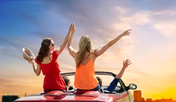 Amigos conduciendo en coche descapotable durante la puesta del sol — Foto de Stock