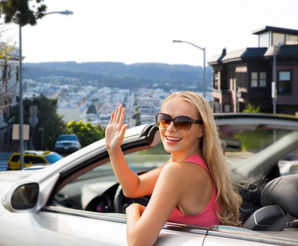 Heureuse jeune femme en convertible voiture agitant la main — Photo