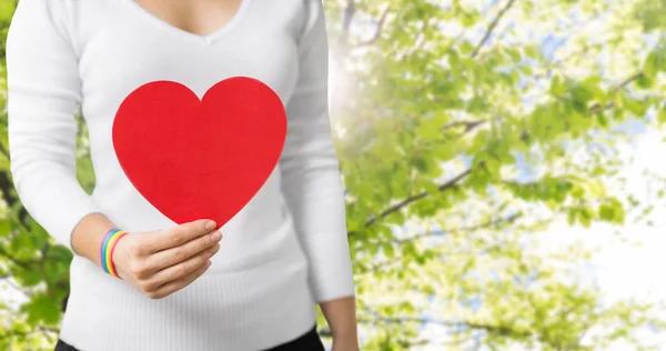 Woman with gay awareness wristband holding heart — Stock Photo, Image