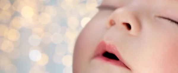 Close up of sleeping baby boy face over lights — Stock Photo, Image