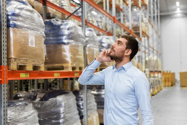 Businessman calling on smartphone at warehouse — Stock Photo, Image