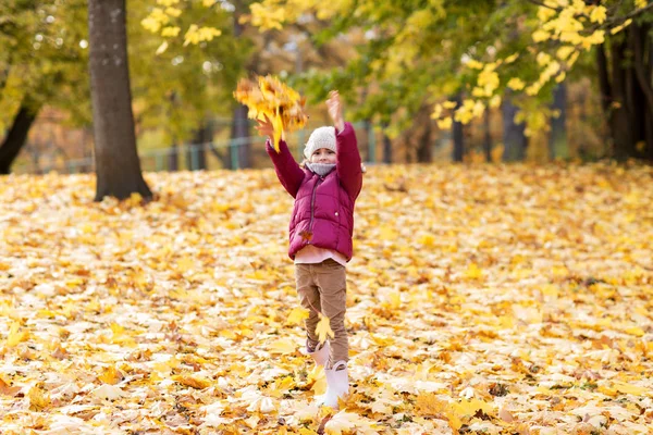 Happy girl playing with leaves at autumn park — Stock Photo, Image