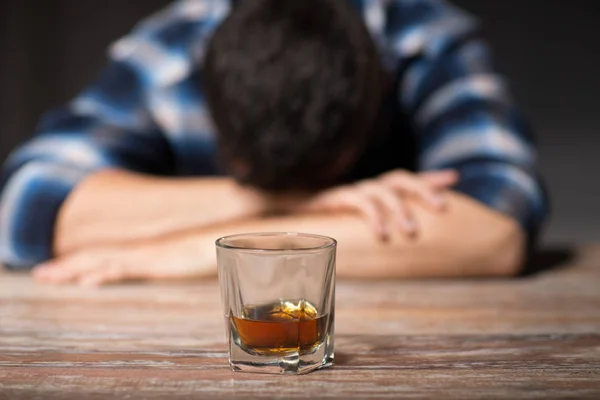 Homem bêbado com copo de álcool na mesa à noite — Fotografia de Stock