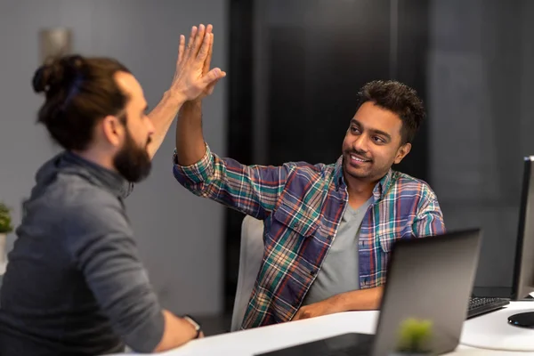 creative team making high five at night office