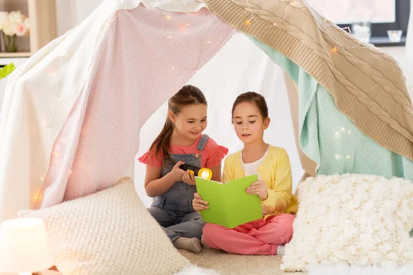 Little girls reading book in kids tent at home — Stock Photo, Image