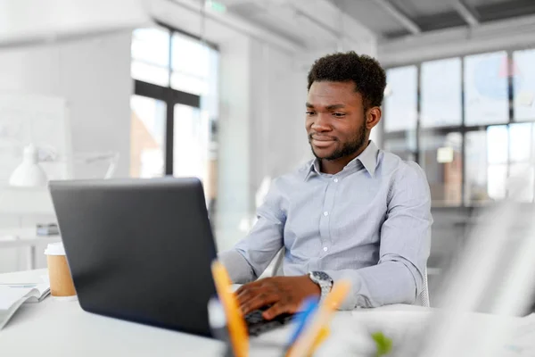 Empresário afro-americano com laptop no escritório — Fotografia de Stock