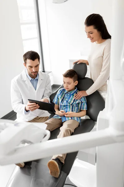 Dentista mostrando tablet pc para criança na clínica odontológica — Fotografia de Stock