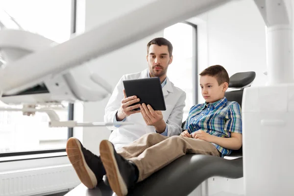 Dentista mostrando tablet pc para paciente criança na clínica — Fotografia de Stock