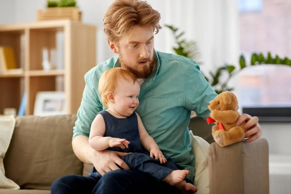 Far och baby dotter med teddybjörn hemma — Stockfoto