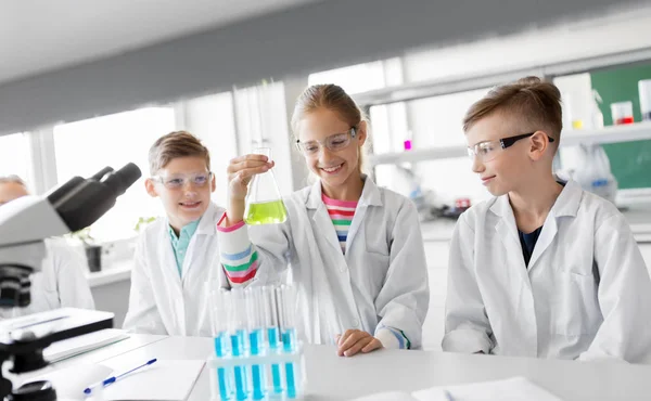 Niños con tubos de ensayo que estudian química en la escuela — Foto de Stock