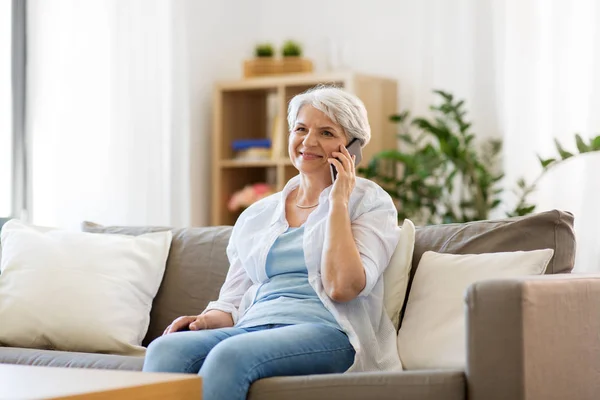 Senior woman calling on smartphone at home — Stock Photo, Image