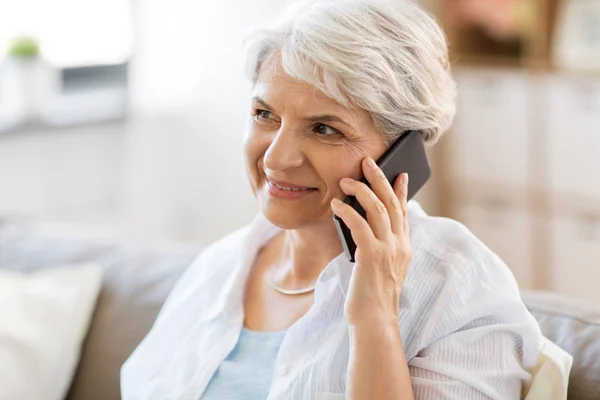 Пожилая женщина звонит на смартфон дома — стоковое фото