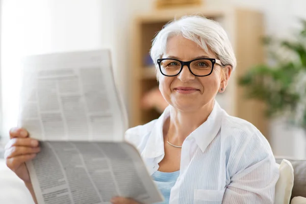 Porträtt av senior kvinna läsa tidningen hemma — Stockfoto