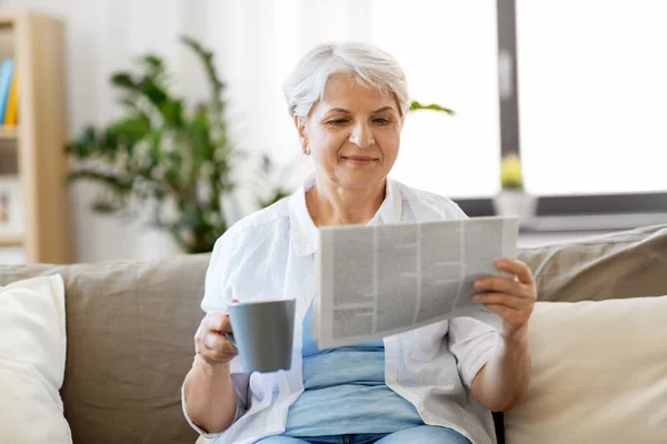 Старша жінка з газетою для читання кави вдома — стокове фото