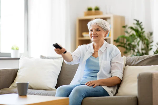 Seniorin mit Fernbedienung zu Hause fernsehen — Stockfoto