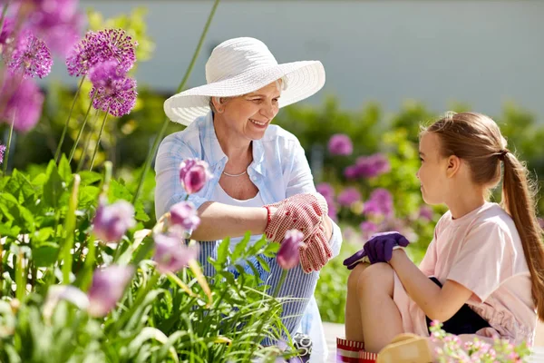 Mormor och flicka med blommor på sommaren garden — Stockfoto