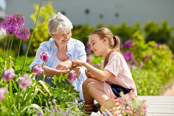 Mormor och flicka sådd blommor på garden — Stockfoto
