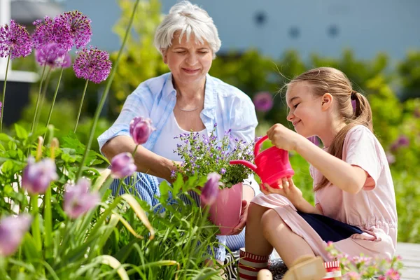 Mormor och flicka plantera blommor på garden — Stockfoto