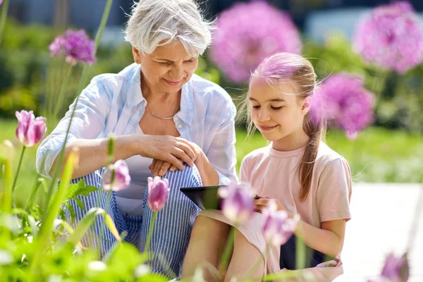 Großmutter und Mädchen mit Tablet-PC im Garten — Stockfoto