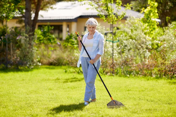 Femme âgée avec râteau de pelouse travaillant au jardin — Photo