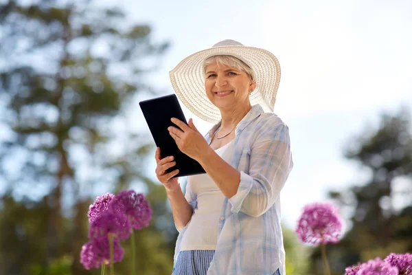 タブレット pc とガーデンで花を持つ年配の女性 — ストック写真