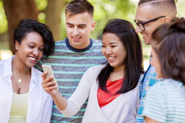 Groep gelukkige vrienden met smartphone outdoors — Stockfoto