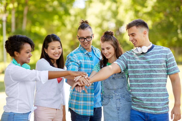 Happy vrienden stapelen handen in park — Stockfoto