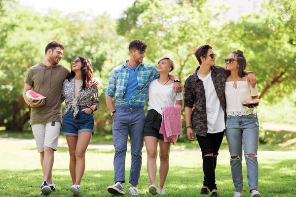 Happy friends with picnic blanket at summer park — Stock Photo, Image