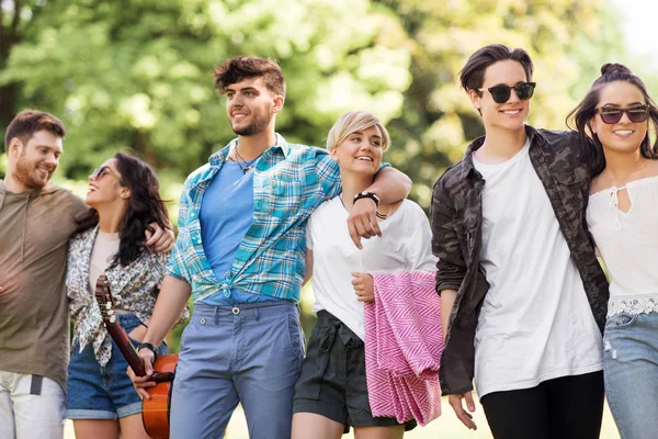 Přátelé s kytarou a piknik deka v parku — Stock fotografie