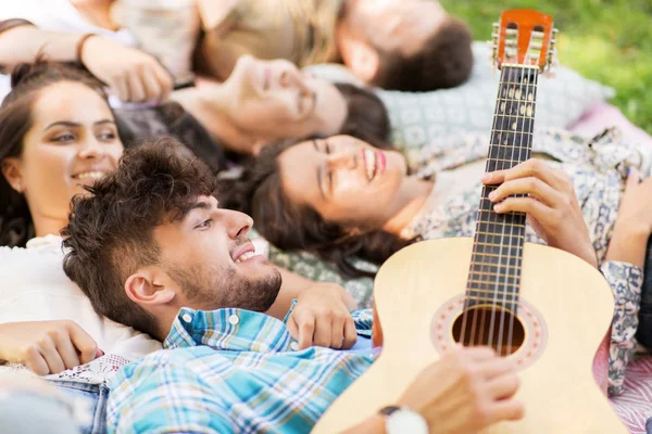 Друзья играют на гитаре и чилингуют на одеяле — стоковое фото