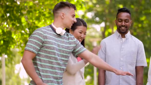 Happy vrienden stapelen handen in zomer park — Stockvideo