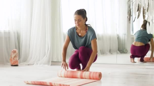 Vrouw oprollen mat te plaatsen bij yogastudio of sportschool — Stockvideo