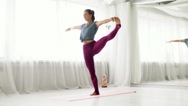 Woman doing yoga hand-to-big-toe pose at studio — Stock Video