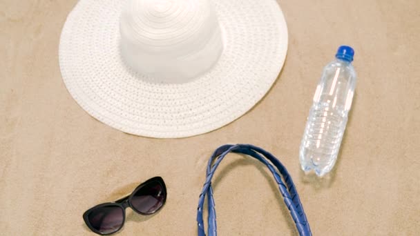 Torba plażowa, filtry przeciwsłoneczne, okulary przeciwsłoneczne i kapelusz na piasku — Wideo stockowe