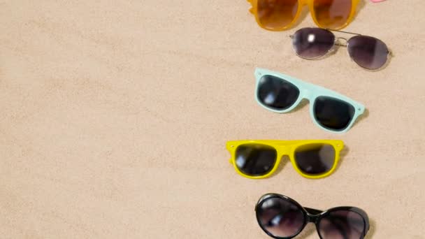 Vari occhiali da sole sulla sabbia della spiaggia — Video Stock