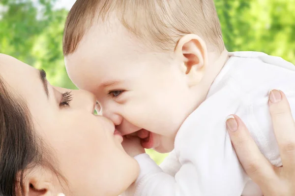 Mãe beijando bebê sobre fundo natural verde — Fotografia de Stock