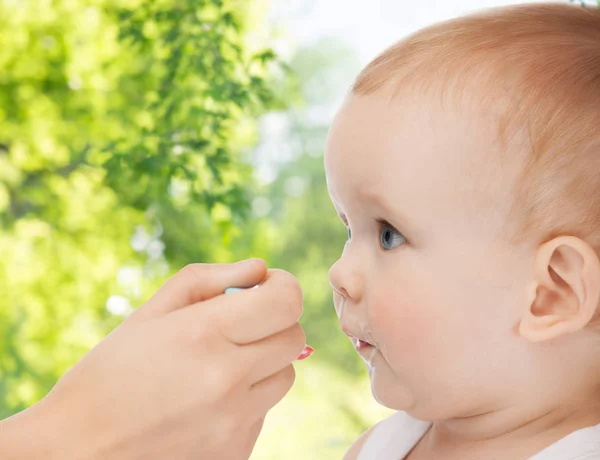 Mão mãe com colher alimentando bebê pequeno — Fotografia de Stock