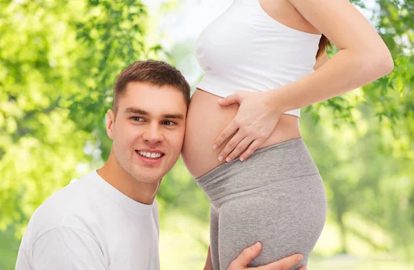 Pai feliz ouvindo barriga de sua esposa grávida — Fotografia de Stock