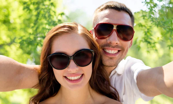 Sonriente pareja usando gafas de sol haciendo selfie — Foto de Stock