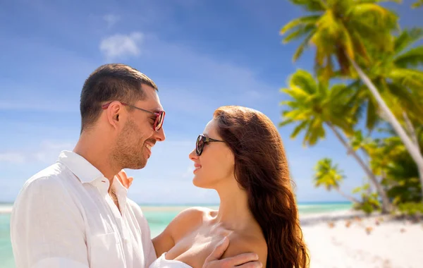 Счастливая пара в солнечных очках над тропическим пляжем — стоковое фото