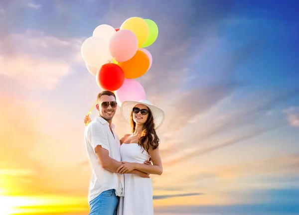 Feliz pareja con globos sobre el cielo puesta de sol —  Fotos de Stock