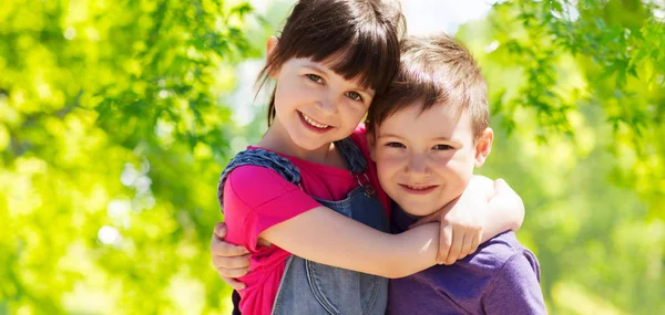 Niños felices abrazándose sobre fondo verde natural Imagen De Stock